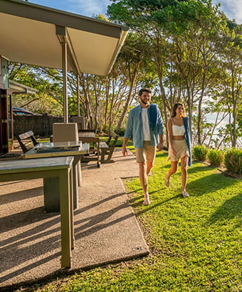 A man and woman walk in front of the verandah at Mildenhall Cottage in Cape Byron State Conservation Area. Photo: John Spencer/DPIE
